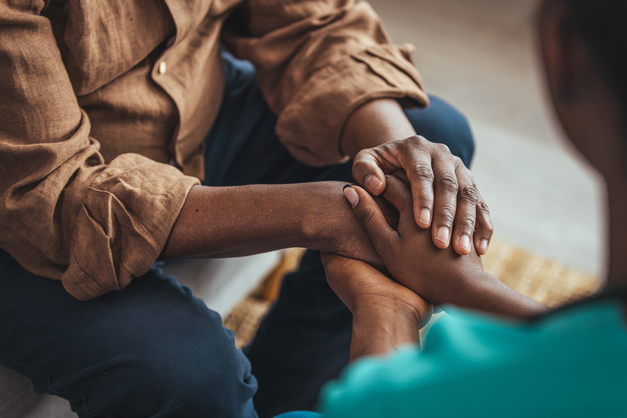 Close-up of two people holding hands, offering comfort and support