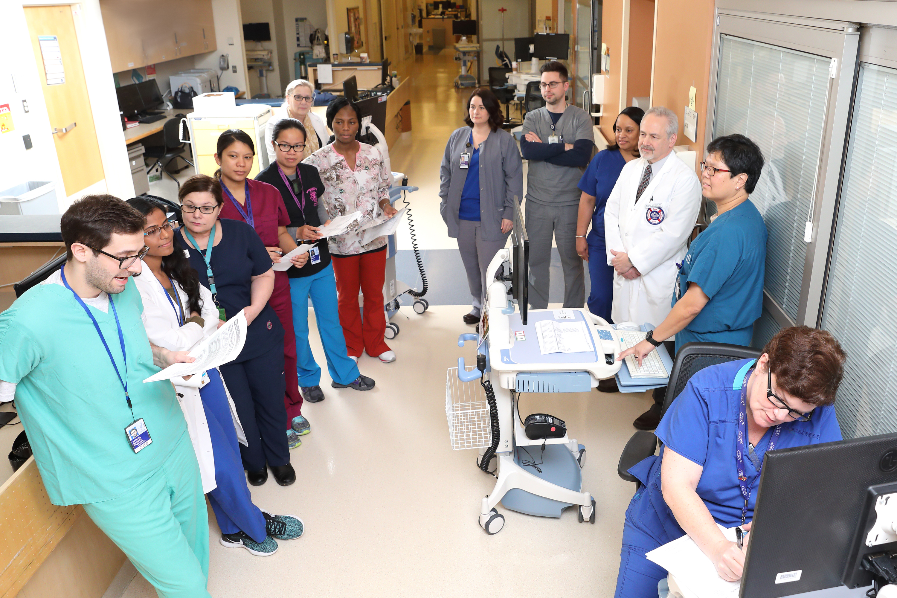 Several staff members of the Critical Care team hold an impromptu meeting in a hallway.