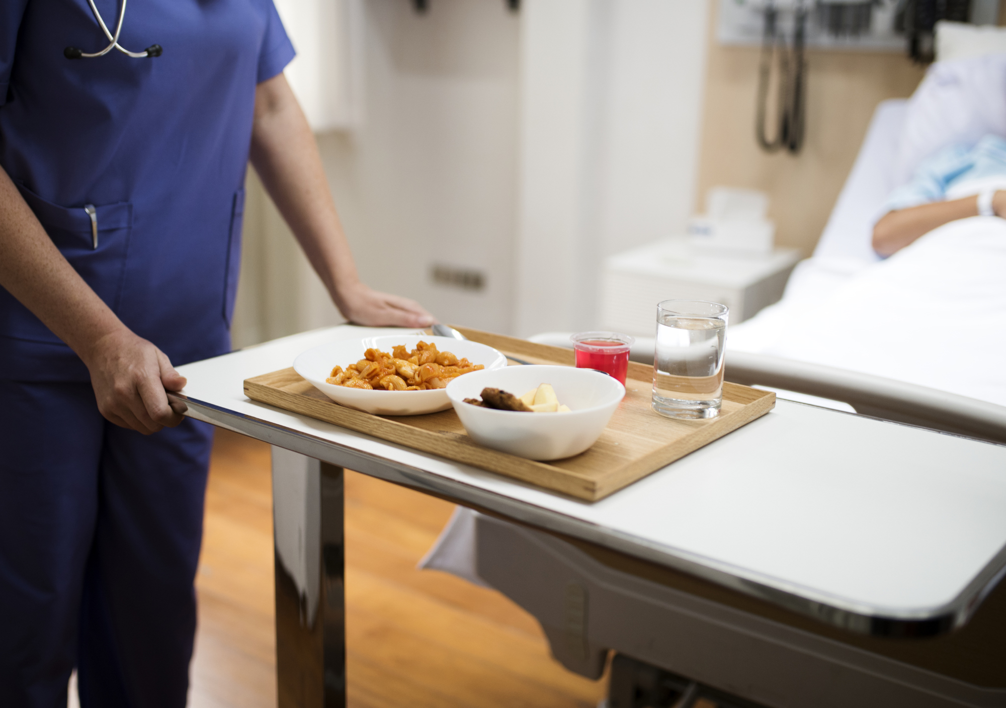 A nutrition staff member delivers a tray of food to a patient.