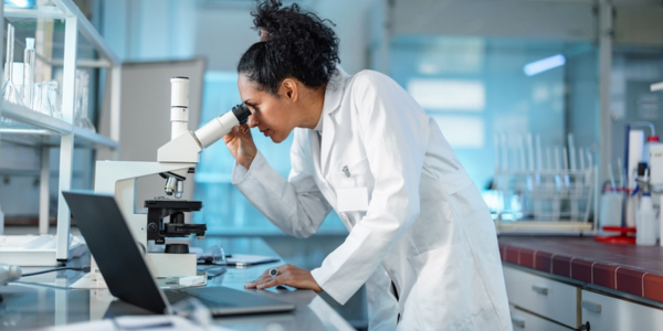 researcher in lab looking through a microscope