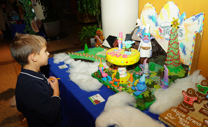young boy admires gingerbread house