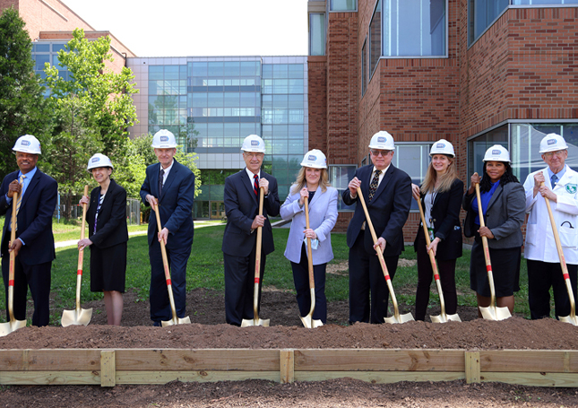 nine individuals holding shovels for groundbreaking ceremony