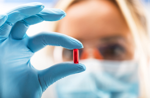a gloved medical professional holding a capsule