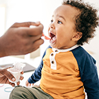 small child being fed yogurt