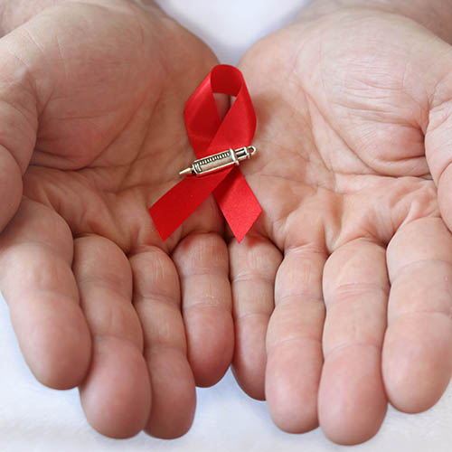 hands holding red ribbon with syringe icon