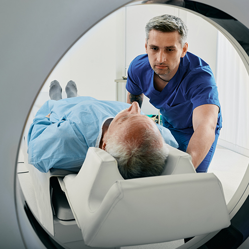 tech assisting patient into CT scan machine