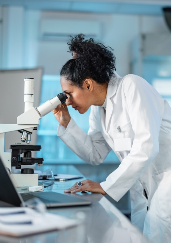 Researcher looking through microscope in lab.