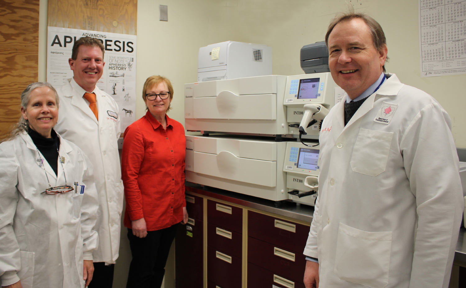 Betsy Furlong, Dr. Mike DeVan, Sherry Sheldon and Dr. Bill Flegel gather near the UV Illuminator, the main hardware component of the INTERCEPT Blood System.