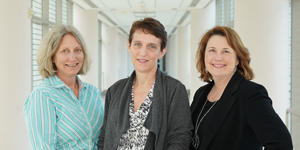 Karen Baker, Dr. Colleen Hadigan and Victoria Anderson stand in a hallway.