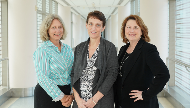 Karen Baker, Dr. Colleen Hadigan and Victoria Anderson stand in a hallway