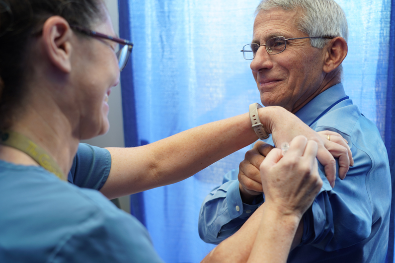 A nurse provides Dr. Anthony Fauci a flu shot