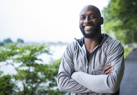 man smiling, arms crossed, on a jogging path