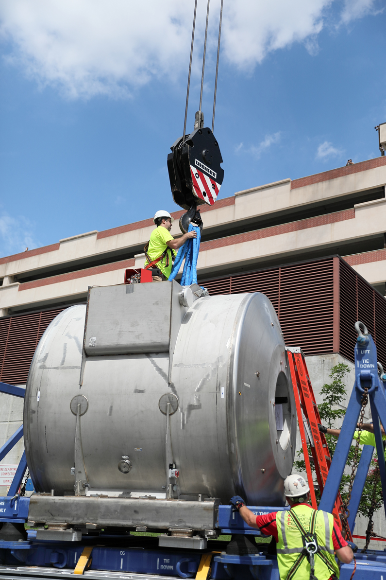 One man on top of the magnet secures a crane attachment to the magnet