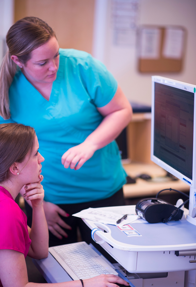 Two care providers look at a computer