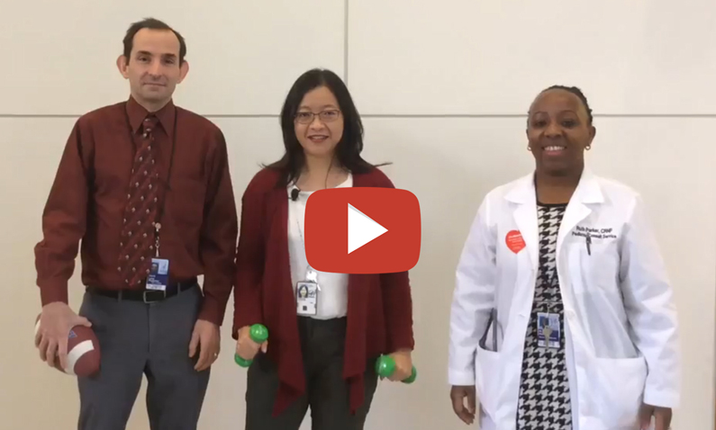 Three staff members working in the Clinical Center stand together as they record a video pledging to move with heart