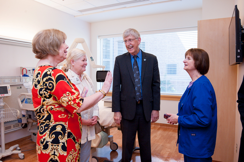 Three women and one man in the empty patient room of the new hospice suite talking