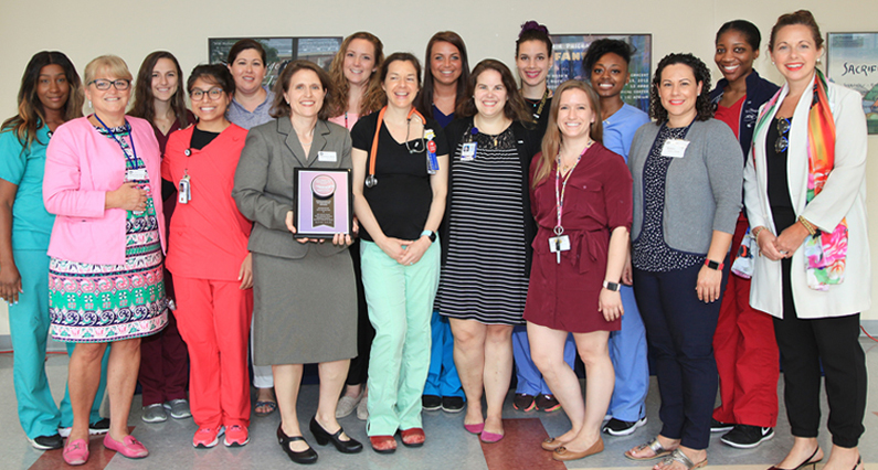 Sixteen women, graduates of the program and departmental leaders, gather for a photo