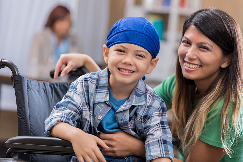 nurse kneeling beside a pediatric patient in a wheelchair