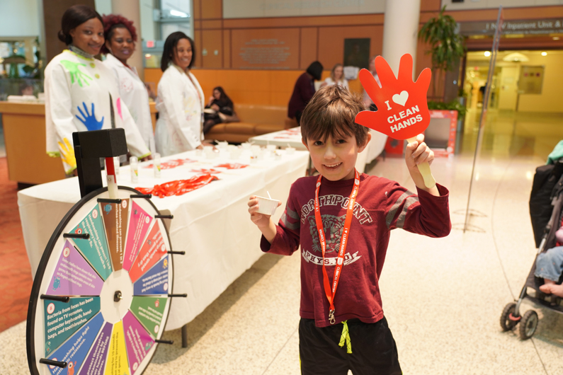 Young boy holds up a sign that says I love clean hands