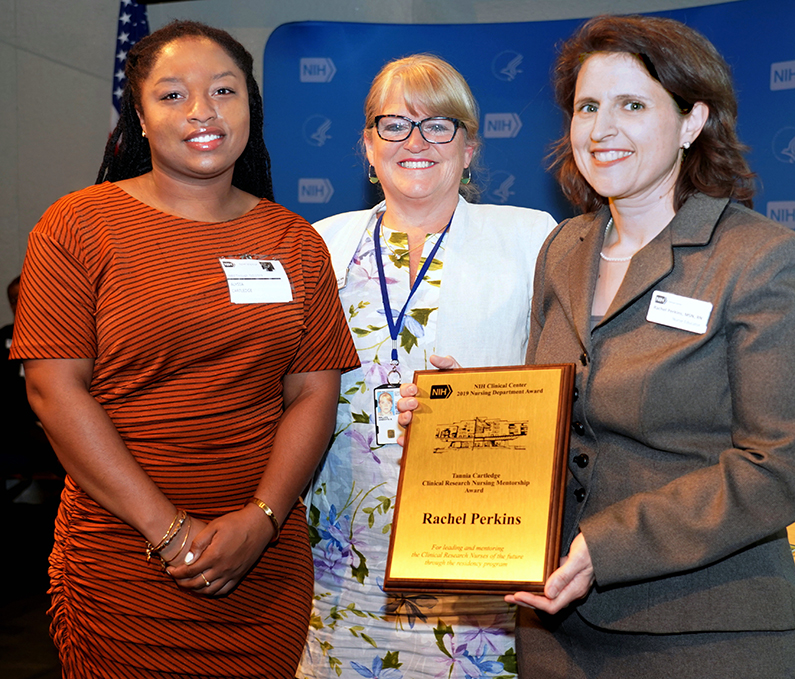 Three women photographed with an award