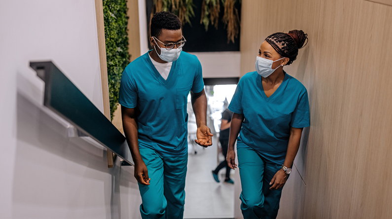 Two hospital staff members converse as walk