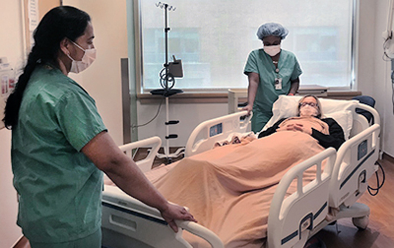 Hospital staff move a patient bed