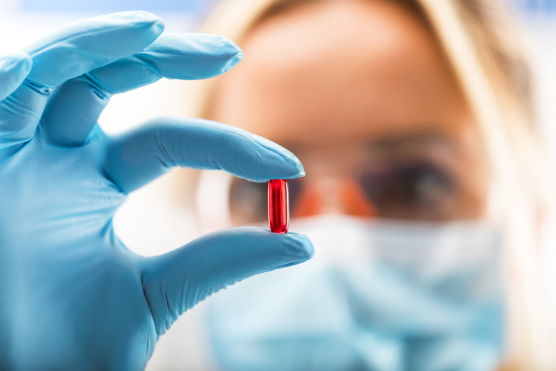 a gloved medical professional holding a capsule