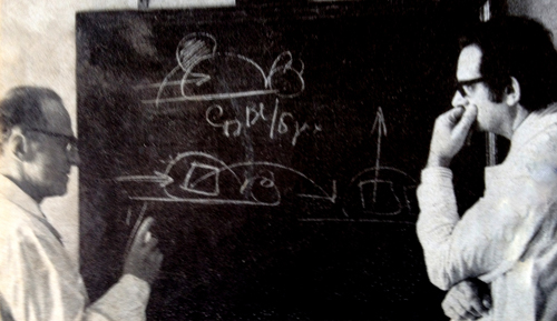 Dr. Holland and a colleague writing notes on a chalkboard