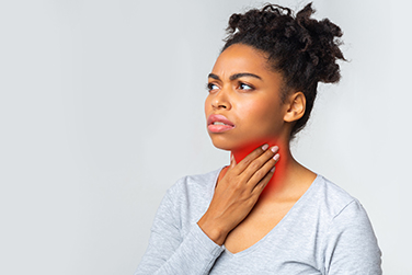 A woman holding her swollen thyroid/neck