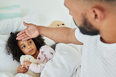 A father checking his child's forehead temperature for a fever