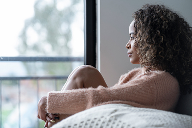 Close-up of a woman looking out a window, reflecting a sense of loneliness