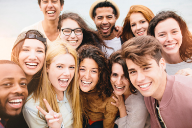 A diverse group of young adult friends smiling and laughing together while posing for a photo outdoors