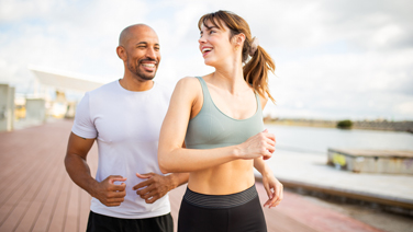 Two people smiling while jogging together outdoors