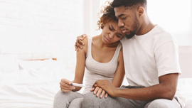 a man and woman looking at a pregnancy test