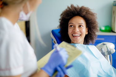 A female patient smiling comfortably while sitting in a dental chair