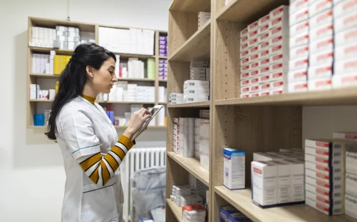 Pharmacist scanning medication on a shelf.