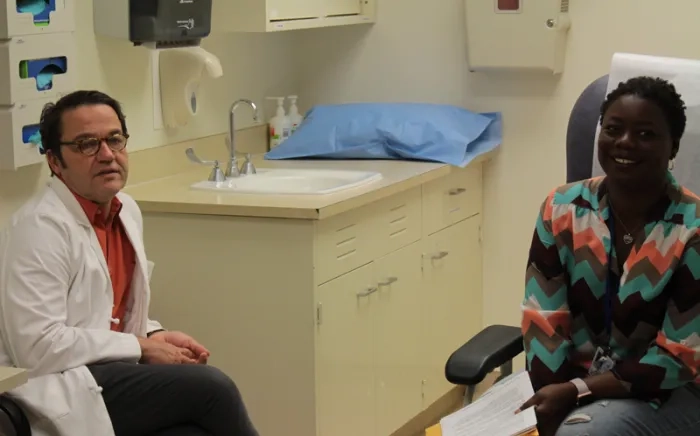 A physician and a patient have a discussion while pausing for a moment to pose.