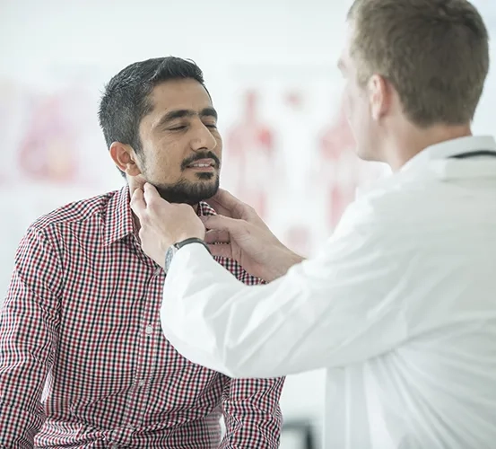 A male patient having his thyroid/neck examined by a doctor