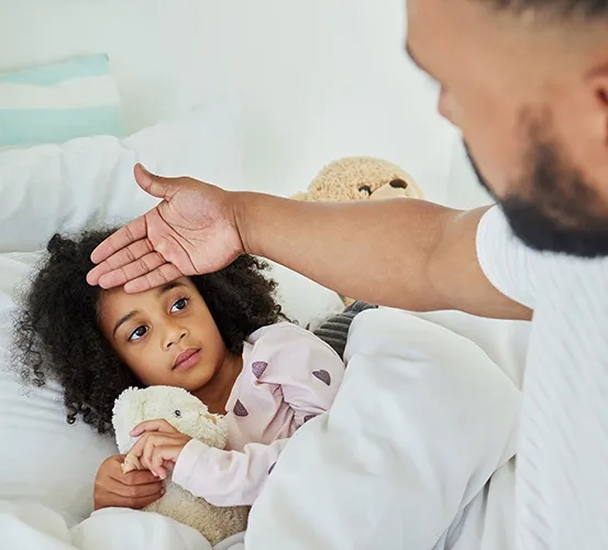 A father checking his child's forehead temperature for a fever