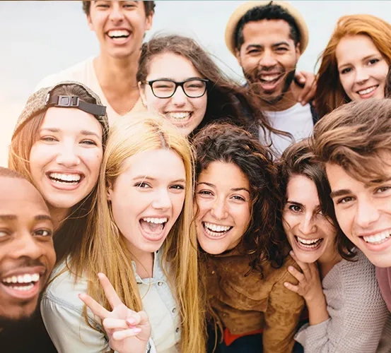 A diverse group of young adult friends smiling and laughing together while posing for a photo outdoors