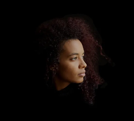 Close-up portrait of a woman with a sorrowful expression, illuminated against a dark background, evoking feelings of loneliness and mental distress