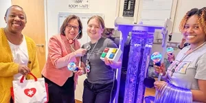 Four medical staff members pose with toys and pediatric medical equipment